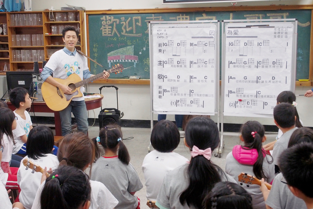 韋禮安老師拿著吉他，跟著頭洲國小的孩子們一起演唱