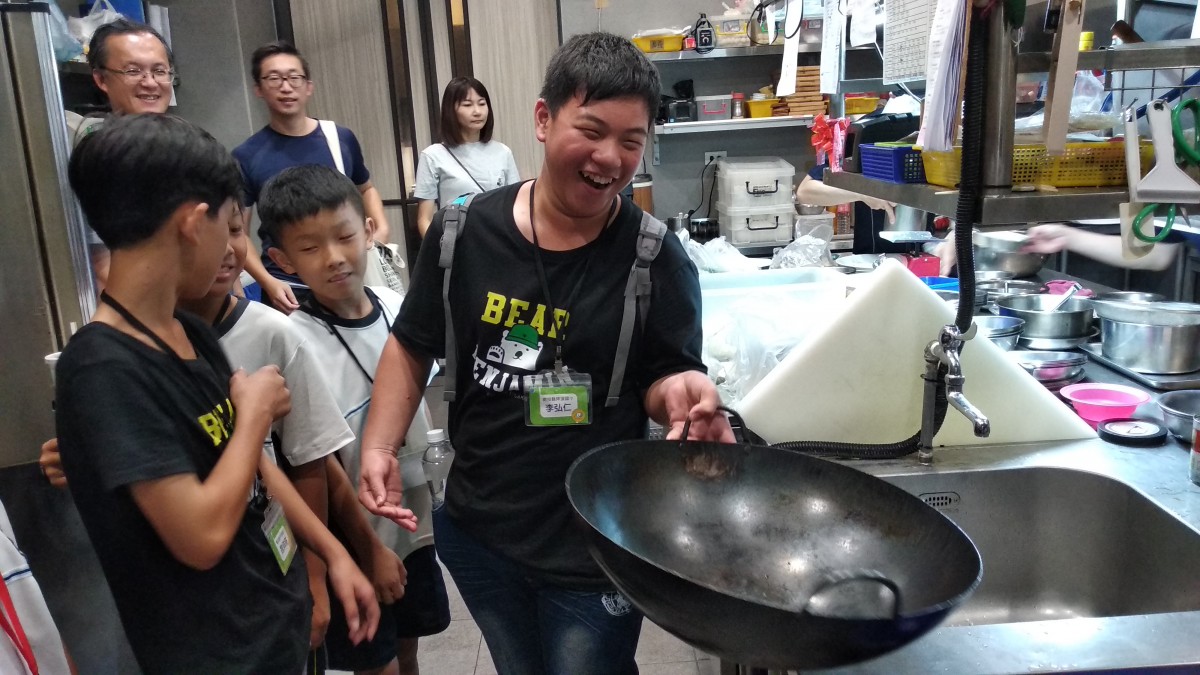 孩子挑戰單手拿鍋具持續一分鐘，體驗每個工作都需要付出投入的練習。
